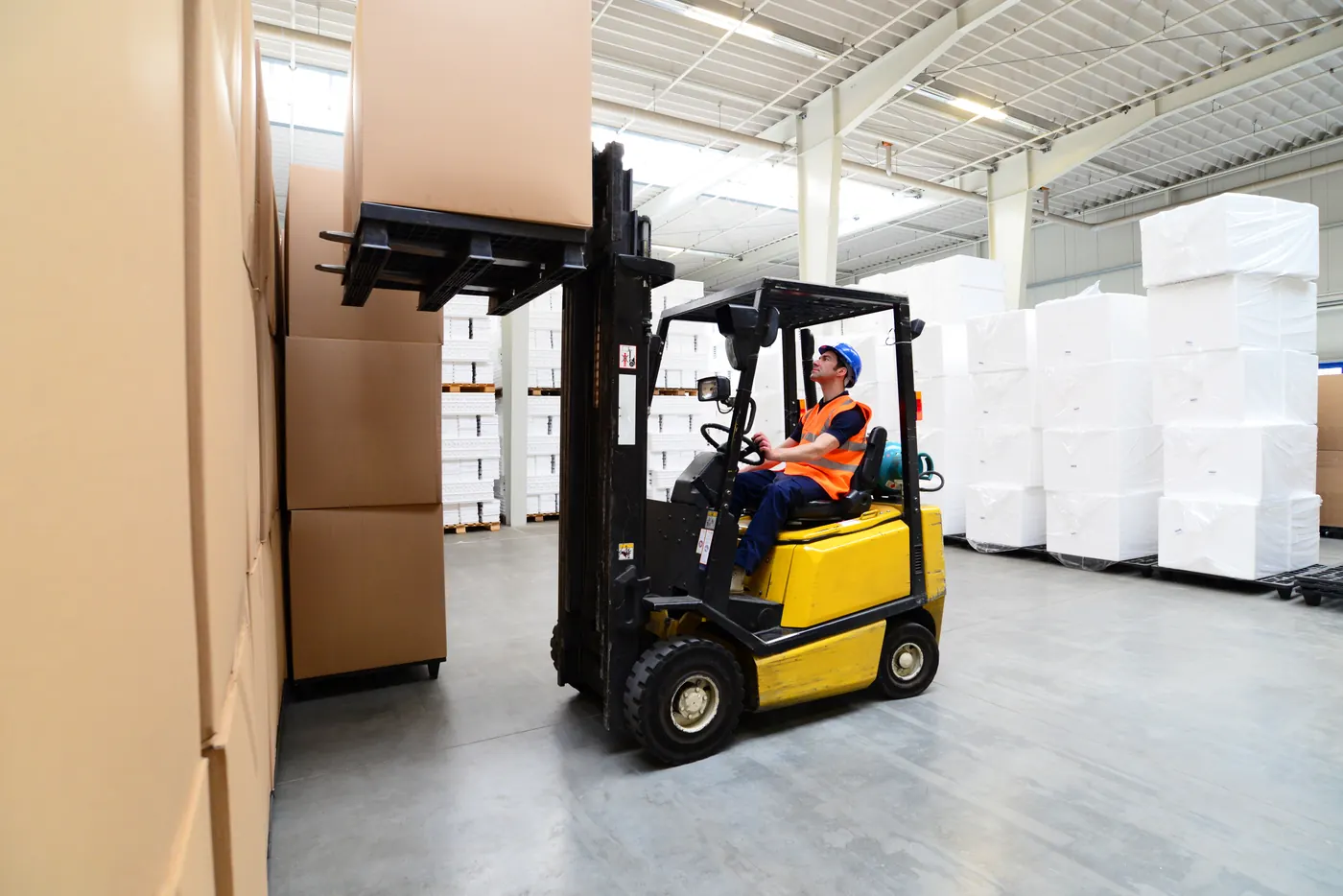 Forklift lifting cartons in a warehouse